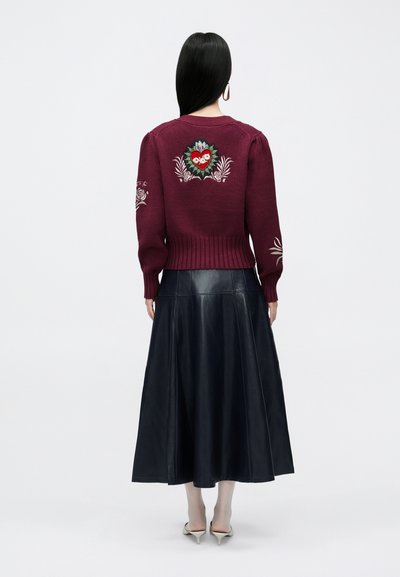Bordowy sweter z dzianiny z kwiatowym haftem na plecach i rękawach, w połączeniu z długą czarną skórzaną spódnicą, miękka tekstura, luźny krój.