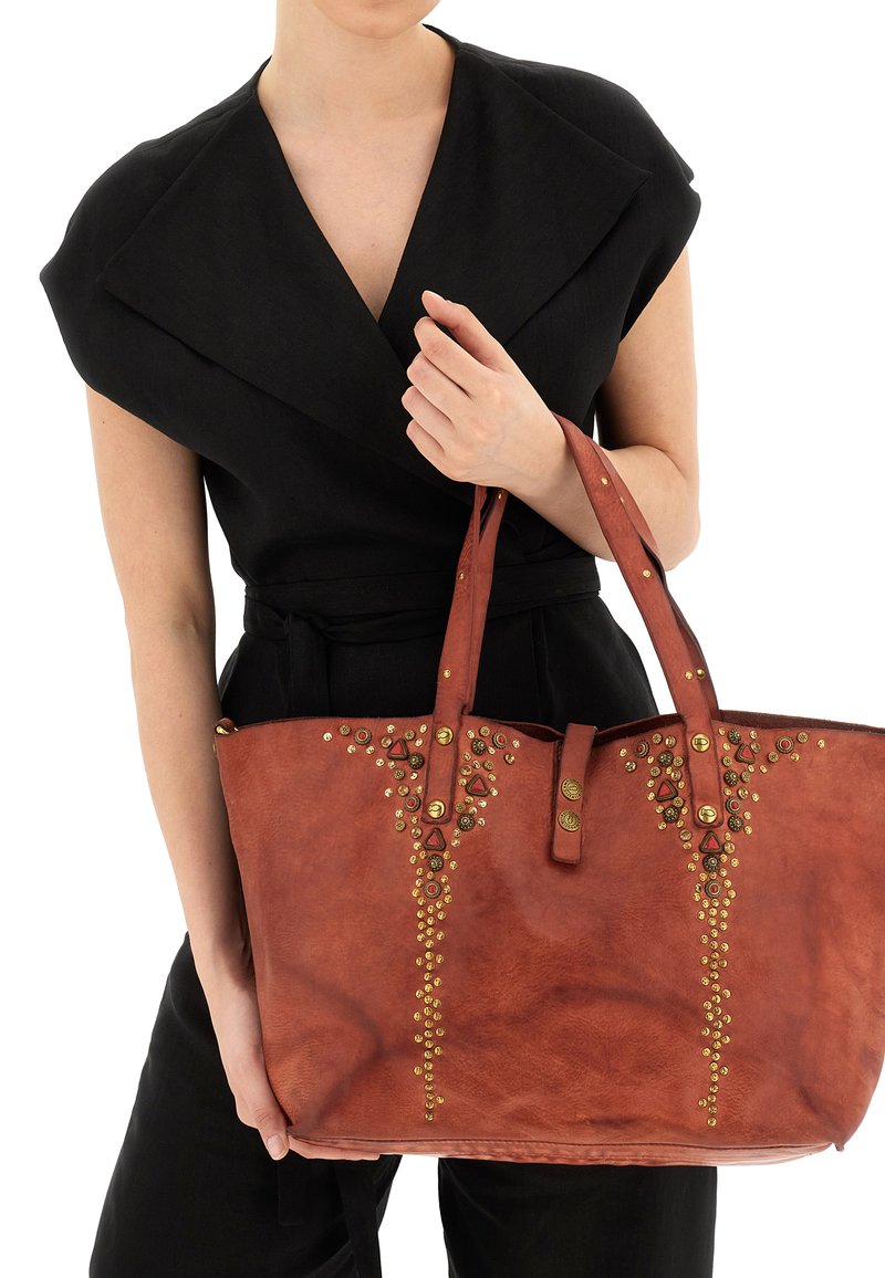 Borsa a tracolla in pelle rossa con finitura testurizzata, dotata di accenti in oro e rosso con borchie in motivi geometrici nella parte anteriore e doppi manici.