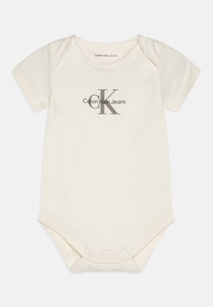 Trumpai rankoviai kreminės spalvos kūdikių bodysuit'as pagamintas iš medvilnės, su subtiliu pilku "CK" logotipu ir spaudėmis apačioje, kad būtų lengva užsidėti.