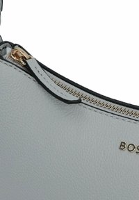 Borsa a tracolla in pelle grigia con superficie testurizzata, dotata di una zip e accessori in oro, rifinita in nero. "BOS" impresso sul lato.