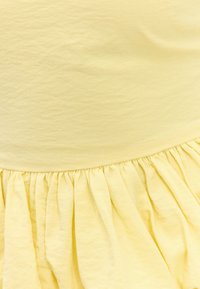 Tissu jaune avec un détail de couture froncée créant de doux plis et une texture.