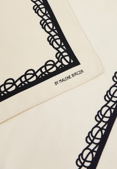 Tissu crème avec un motif de bordure géométrique noire en boucles et « BY MALENE BIRGER » imprimé près du bord.
