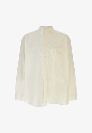 Chemise boutonnée à manches longues de couleur blanc cassé, avec un col pointu et une poche poitrine, présentée sur un fond blanc uni.