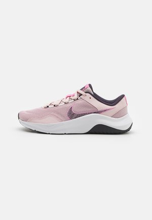 Zapatilla de correr Nike de perfil bajo en rosa y gris con parte superior de malla, suela blanca y cuello acolchado negro, vista lateral.