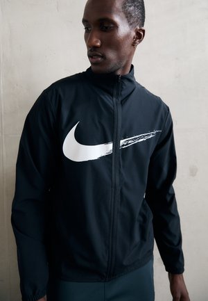 Black zip-up jacket made of lightweight fabric with a white Nike logo on the chest. Features a stand-up collar and long sleeves.