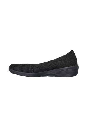 Zapato negro sin cordones con parte superior de tejido y suela baja en cuña, diseñado para la comodidad y uso casual.