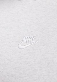 Vit bomull T-shirt med en subtil broderad Nike-logotyp på bröstet, med en slät yta och klassisk rund halsdesign.