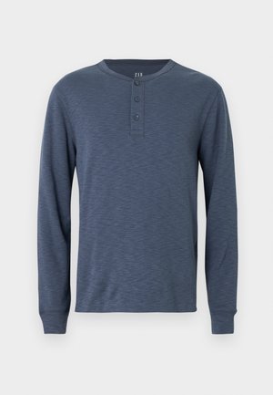 Sötétkék, hosszú ujjú henley ing texturált felülettel, kerek nyakkivágással és háromgombos patenttal a mellrészen.