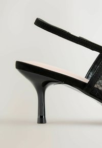 Čierna sandála na vysokom opätku so zvrškom z semišu, priehľadnými sieťovanými detailmi a štíhlym opätkom. Podrážka je svetloružová a mierne polstrovaná.