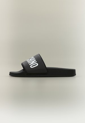 Black slide sandal with thick sole and wide strap featuring white "RHINO" text on a plain neutral background.
