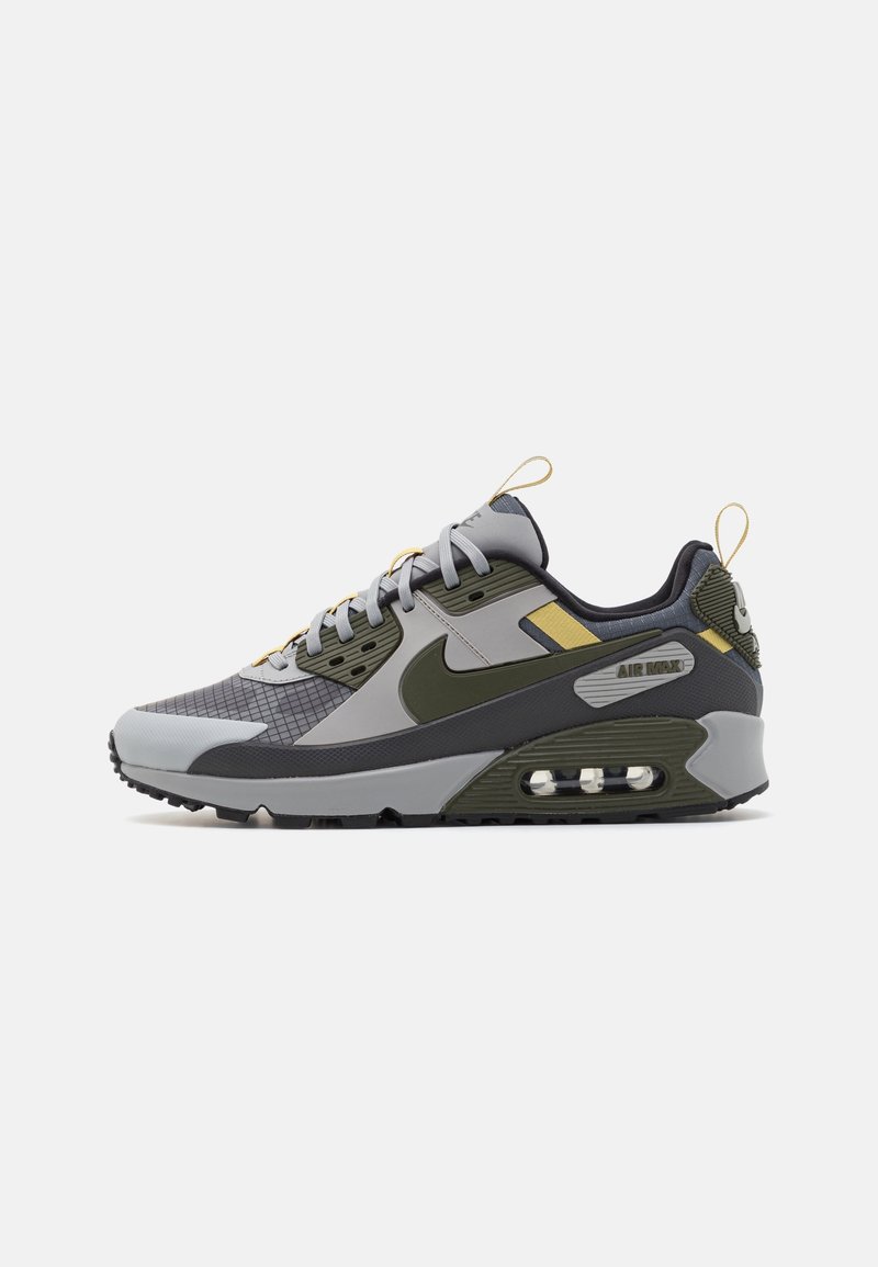 Baskets basses Nike Air Max en gris et vert olive avec semelle noire, amorti à air visible et accents jaunes.