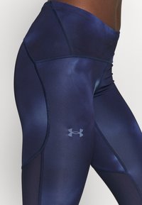 Granatowe legginsy sportowe wykonane z gładkiego, elastycznego materiału z wysokim stanem, z delikatnym logo i kontrastowymi szwami.