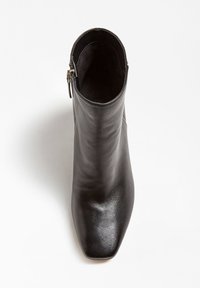 Botín de cuero negro hasta el tobillo con punta cuadrada, textura suave y cremallera lateral. Presenta un tacón bajo y un diseño minimalista.
