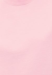 Μονόχρωμο ανοιχτό ροζ ύφασμα με στρογγυλή λαιμόκοψη και διακριτή ραφή γύρω από το λαιμό, λεία υφή, χωρίς σχέδια ή διακοσμήσεις.