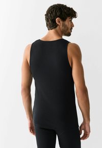 Canotta nera a coste con scollatura tonda e silhouette aderente, realizzata in tessuto liscio e elastico con design senza cuciture.