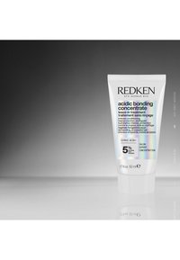 Redken Acidic Bonding Concentrate, 50 ml, witte tube met iriserende accenten, bevat tekst die de leave-in behandeling en belangrijke ingrediënten beschrijft.