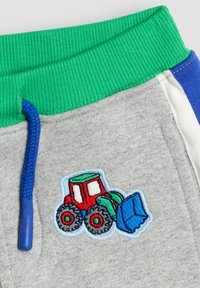 Graue Baumwollshorts mit einem grünen gerippten Bund und einer blauen Kordel. Mit einem bunten Traktor-Stickerei-Detail am Bein.