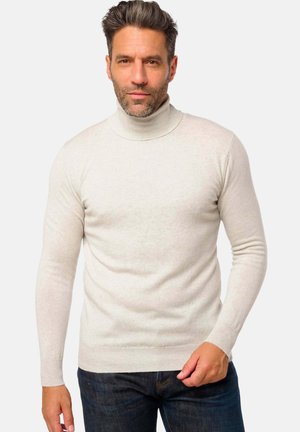 Pull à col roulé beige clair, coupe ajustée, avec des poignets et un ourlet côtelés, fabriqué à partir d'un tissu à la texture douce. Porté avec un jean en denim noir.