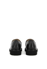 Black leather shoes with a smooth texture, rounded toe, and a thick black rubber sole. The back shows a minimalist design and clean lines.