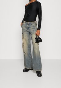 Musta olkaimeton bodysuit, vaaleansiniset cargo-farkut, joissa on haalistunut viimeistely ja useita sivutaskuja, sekä tukevat mustat platform-saappaat.