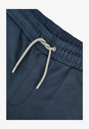 Marineblauwe joggingbroek met een elastische tailleband, voorzien van een trekkoord met beige accenten en metalen aglets. Glad katoenen stoftextuur.