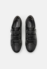 Baskets en cuir noir avec trois sangles velcro réglables, bout rond et semelle en caoutchouc blanche. Logo estampillé sur la semelle intérieure.