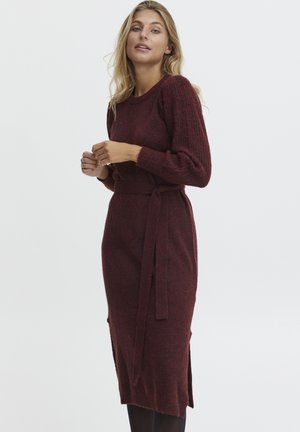 Burgunderfarbendes Strickkleid mit taillierter Passform und seitlichen Schlitzern. Mit langen Ärmeln und einem Bindegürtel. Strukturiertem Stoff mit dezentem Muster.