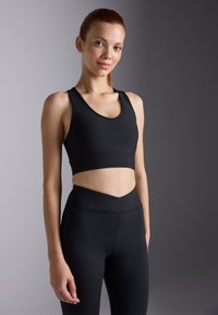 Black athletic crop top with ribbed texture and a v-neck design, paired with high-waisted leggings featuring an angular waistband.