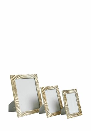 Drei leere goldene Fotorahmen in verschiedenen Größen mit strukturierten, geometrisch gemusterten Rändern stehen auf einer weißen Oberfläche.