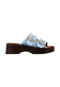 Sandale plateforme à enfiler avec semelle marron foncé, brides en denim bleu clair effiloché et détails de boucle dorée sur fond blanc.