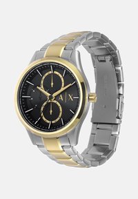 Ura s srebrnim in zlatim tonom iz nerjavečega jekla z črnim številčnikom, tremi podštevilčnicami in srebrnimi oznakami ur. Ima zasnovo zapestnice s povezavami.