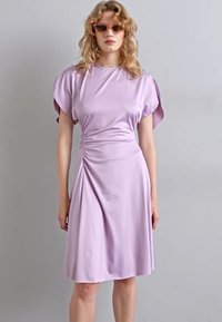 Lilas klänning med korta, puffiga ärmar; rynkad sidodetalj; slät, elastisk tyg; knälång fåll; minimalistisk design.