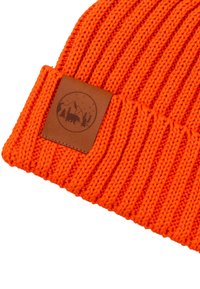 Jasnopomarańczowa prążkowana czapka z dzianiny z podwiniętym brzegiem i brązową skórzaną naszywką z motywem gór, drzew i sylwetki niedźwiedzia.