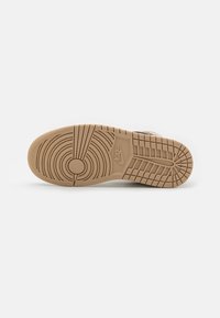 Sole boty Nike, s centrálním kruhovým vzorem, texturovaná guma pro grip a béžová barva s drážkami a akcentovaným logem.