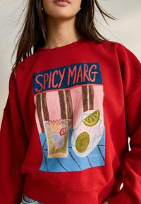 Raudonas džemperis su ryškiu grafinio atspaudu "SPICY MARG", gėrimu ir laimo riekelėmis, pagamintas iš medvilnės, turintis laisvą siluetą.