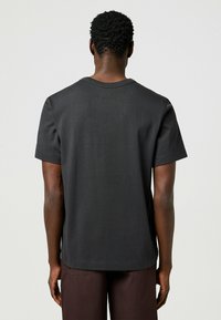 Zwarte T-shirt met korte mouwen van katoen, met ronde hals en rechte zoom, weergegeven vanuit de achterkant met een gladde textuur.