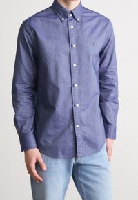 Camicia button-up blu navy, in cotone, maniche lunghe e colletto button-down. Presenta un piccolo logo sul petto e bottoni bianchi.