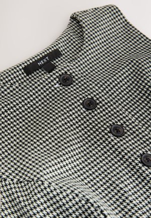 Tissu à motif pied-de-poule en noir et blanc avec une finition texturée. Comprend un col et trois boutons foncés sur le devant.