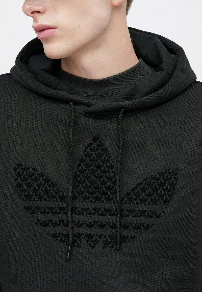 Black hoodie with a large, textured black leaf logo on the front; features a drawstring hood and a ribbed collar.