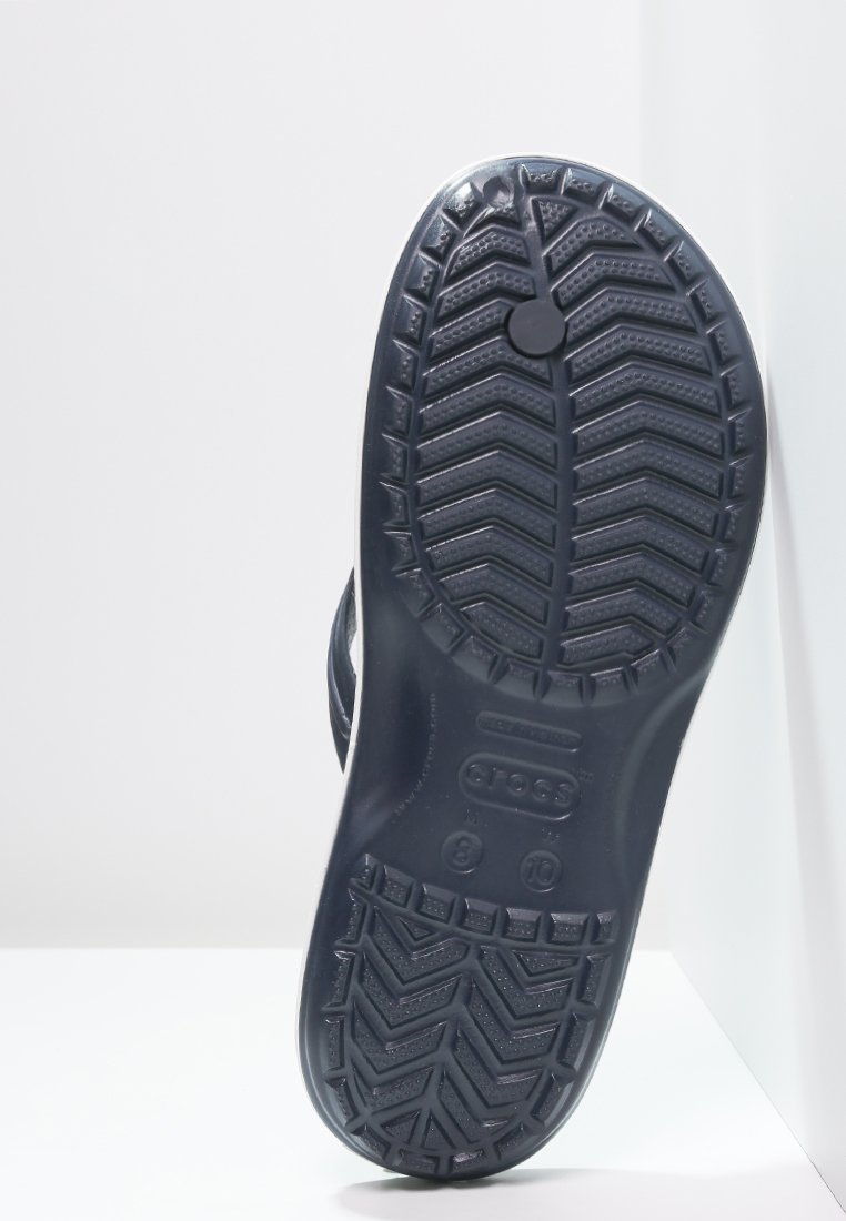 Suela de zapato de goma negra con un diseño de huella texturizado y con patrón. Presenta un logotipo circular y marcas de tamaño cerca del talón.