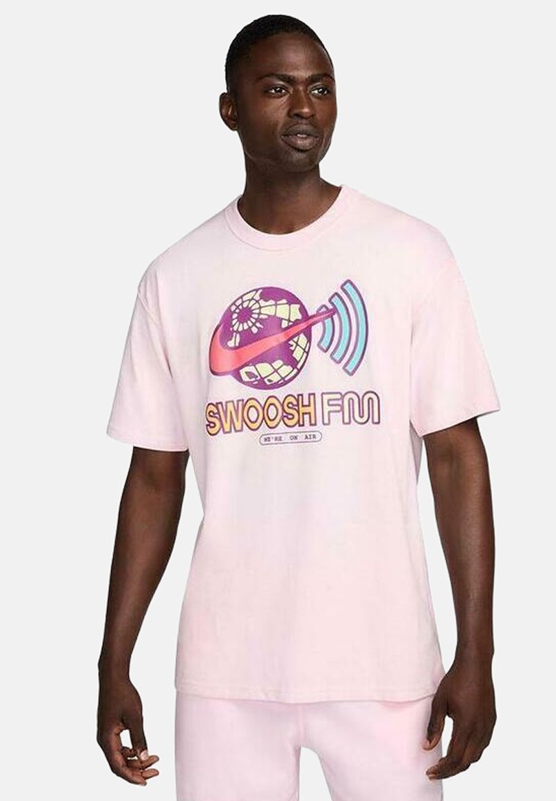 Camiseta de algodón rosa claro con un diseño gráfico de un globo terráqueo y ondas sonoras, con el texto "SWOOSH FUN" en colores vibrantes. Manga corta, corte relajado.