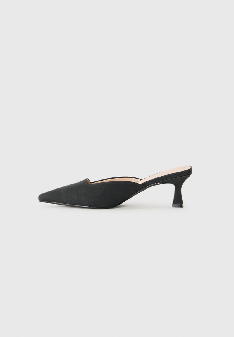 Black pointed-toe mule shoe with low kitten heel and open back on a plain light background.