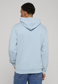 Sweat à capuche bleu clair avec cordon de serrage à la capuche, poignets et ourlet côtelés, fabriqué en tissu doux. Présente un design minimaliste sans motifs ni impressions.