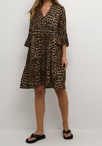 Leopardenmuster-Kleid mit V-Ausschnitt, dreiviertel langen Glockenärmeln und gestuftem Saum. Aus leichtem Stoff gefertigt, in Schwarz- und Brauntönen.