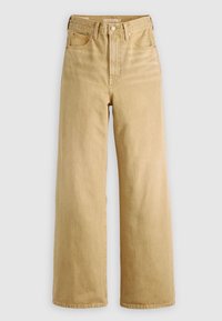 Jean beige taille haute à jambes larges avec bouton à l'avant, passants pour ceinture et design à cinq poches sur fond uni.
