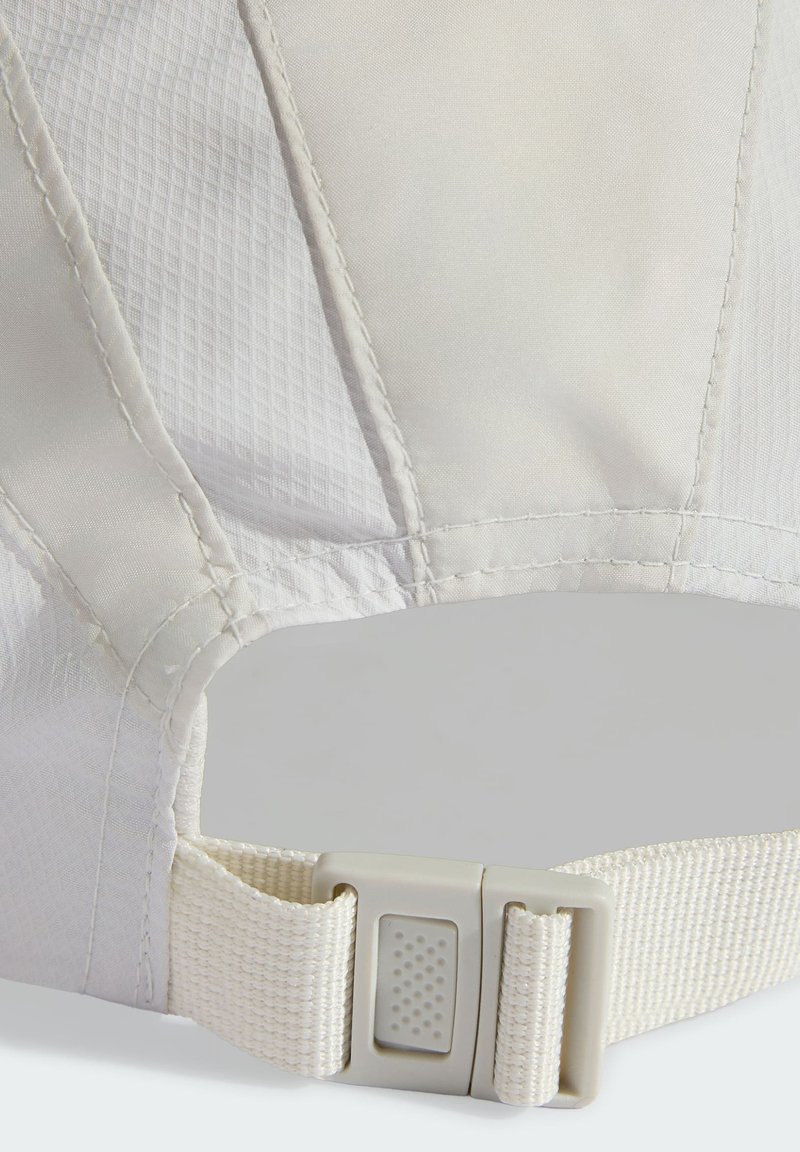 Sangle en tissu blanc réglable avec boucle en plastique à dégagement rapide à l'arrière d'une casquette blanche texturée.
