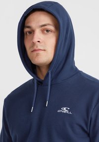 Hoodie bleu marine avec cordons de serrage, arborant un logo O'Neill blanc sur la poitrine. Tissu doux, coupe décontractée et design avec poche kangourou.