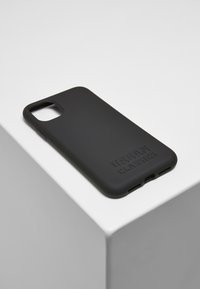 Coque de téléphone en silicone noir avec une finition mate, présentant un logo en relief subtil et des découpes pour les boutons et les ports.