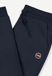 Temno modri športni hlače iz mehkega materiala, s plišastim pasom na vrvico, dvema stranskima žepoma in okroglo aplikacijo logotipa Colmar.