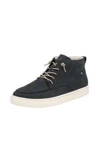 Bottes noires en cuir à la cheville avec des lacets beiges, bout arrondi, semelle en caoutchouc blanche et une boucle à l'arrière pour faciliter l'enfilage.